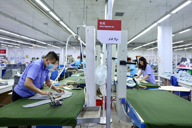 工人在鄂尔多斯羊绒集团工厂生产线上熨烫衣物。本报记者 蒋雨师摄