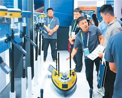  近日，第五届北斗规模应用国际峰会在湖南省株洲市举办。图为观众在展区了解一款无人测量船。新华社记者 陈振海摄