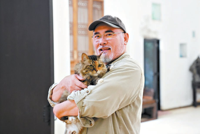 赵文瑄在家中和爱猫在一起。于他而言，这些小生命是朝夕相伴的家人。本报记者 崔家宁 摄