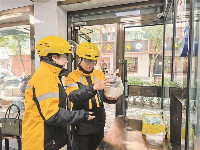 记者（图左）体验外卖骑手取餐过程。   实习生 刘春阳 摄