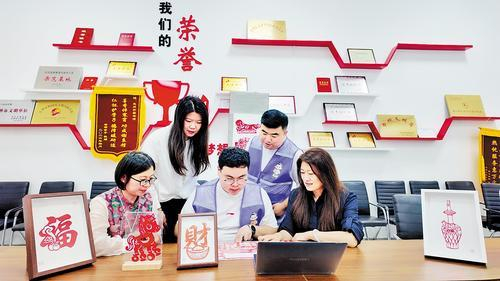     9月29日，在定州市图书馆，石家庄科技信息职业学院青年创业者刘子哲（前排中）与指导老师一起研究剪纸作品。受访者供图
