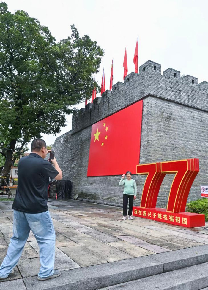 10月1日，游客在浙江嘉兴子城遗址公园与祝福祖国的装置合影。新华社记者 徐昱 摄