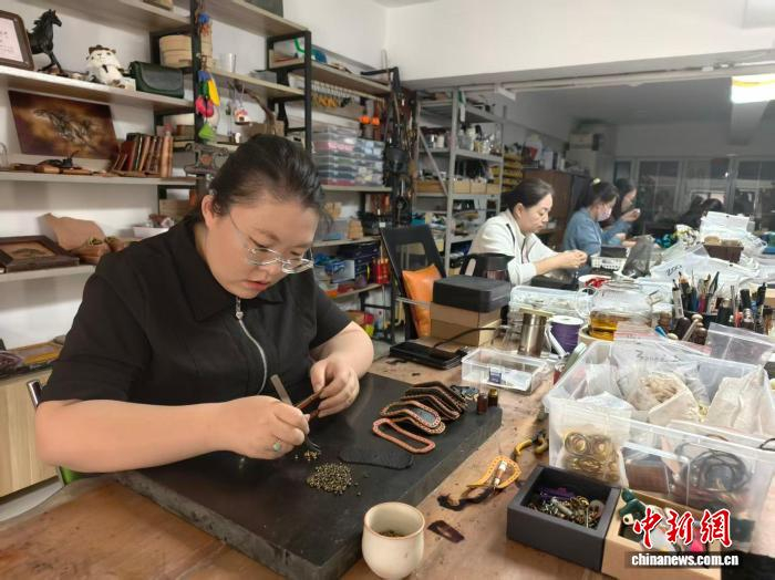 　　9月21日，内蒙古自治区通辽市经济技术开发区新城街道河畔花园内，当地居民正在制作皮雕产品。中新网记者 勉征 摄