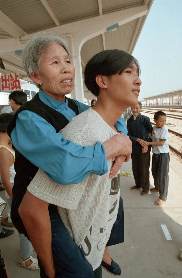 1996年，江西赣南地区赣州工人刘峻背着七十多岁的奶奶专程赶到赣州火车站看火车。