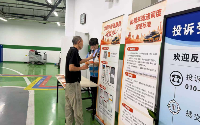 一名出租车驾驶员现场了解出租车短途复载应用的使用方法。北京市重点站区管委会供图
