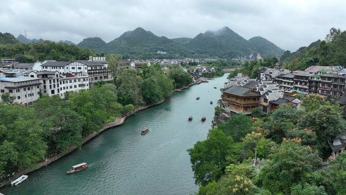 图为游客在重庆市秀山土家族苗族自治县洪安古镇景区乘坐游船游览。（无人机照片 胡程 摄）