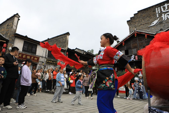图为游客在重庆市秀山土家族苗族自治县洪安古镇边城景区观看打苗鼓表演。（胡程 摄）