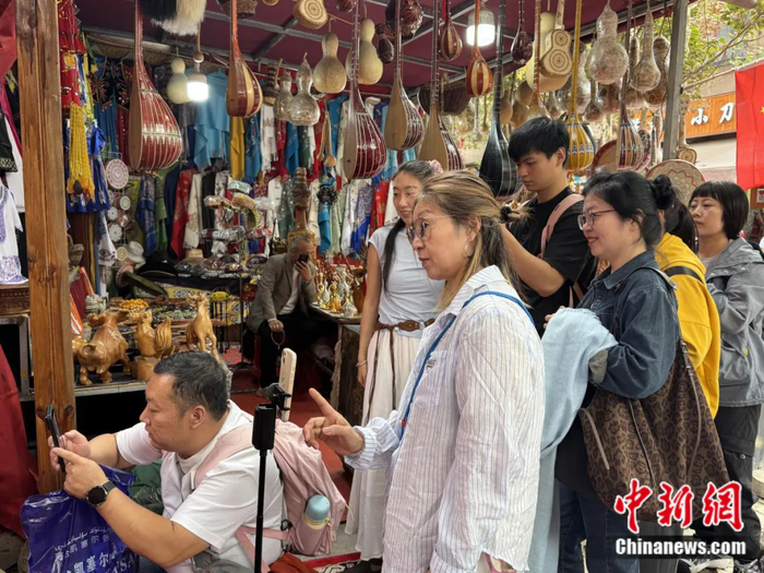 在喀什古城的巴扎集市，摊位上方悬挂着传统弹拨乐器。贾志鹏 摄