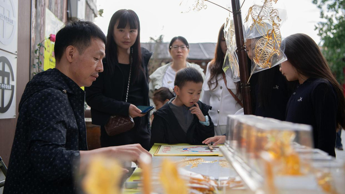 10月3日，游客在河南新郑东门东里创意街区购买糖人。 新华社发（孔维钾摄）