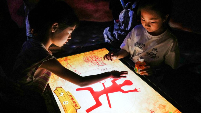 10月2日，在广西壮族自治区博物馆，两名儿童借助智能设备学习制作花山岩画中的图腾。新华社记者 张爱林 摄