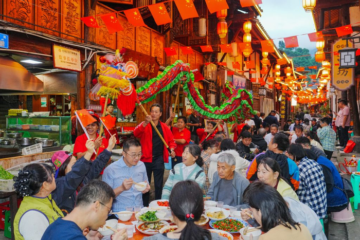 10月1日，在重庆市北碚区金刀峡镇偏岩古镇长街宴上，民间艺人表演舞龙。新华社发（秦廷富 摄）