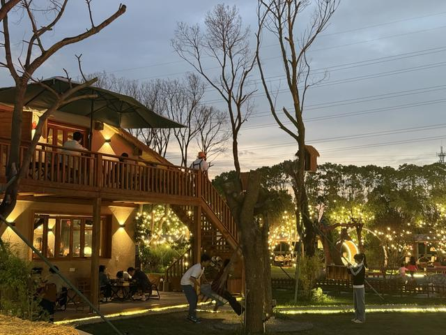 夜晚，沿河错落的餐位与几座树屋被暖黄灯串点亮（沈思怡 摄）