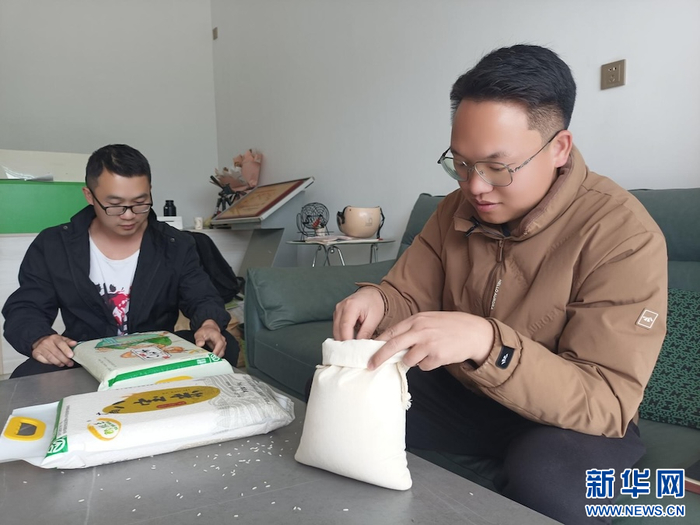 罗明达查看稻米成色（资料图）。新华网发（广南县融媒体中心 供图）