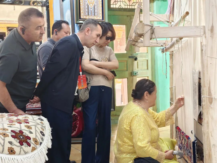 ▲与会代表在团城观看手工艺人现场展示《五星出东方利中华》织锦技艺。王珍摄