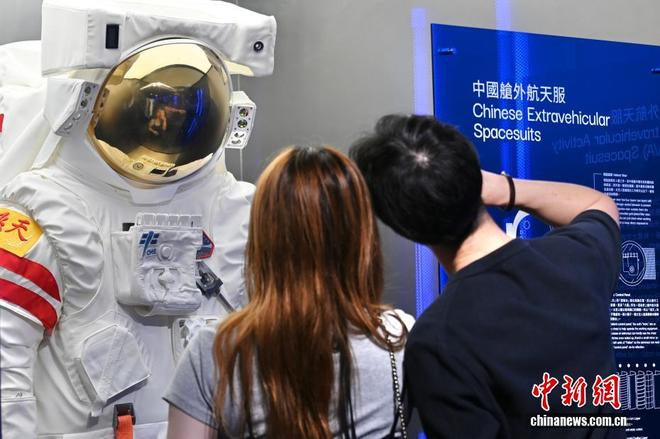  中新网记者 李志华 摄 图为现场人士与“中国舱外航天服”展品合影。