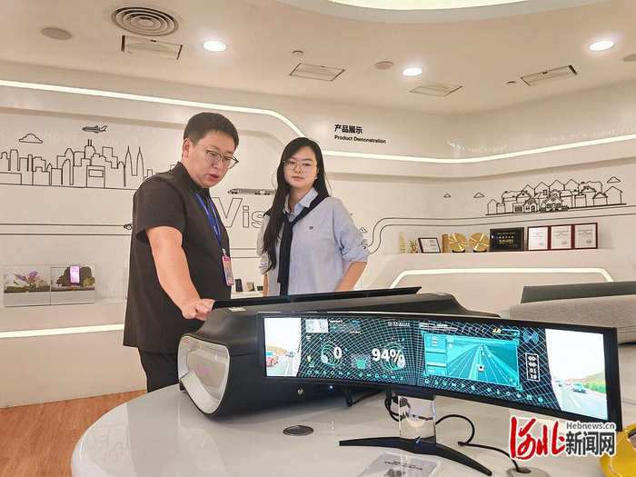 10月8日，云谷（固安）科技有限公司工作人员（左）向客户介绍企业生产的柔性显示屏。河北日报记者 刘 杰摄