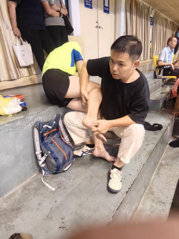 作为广东省毽球队特聘队医,陈泽尧在比赛场边为运动员查看脚踝。