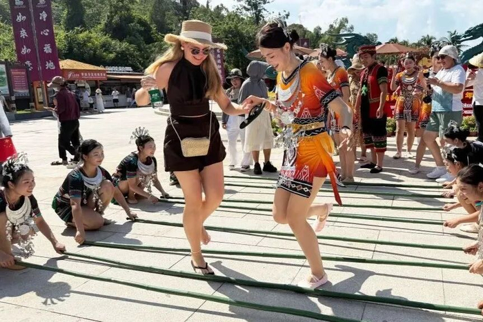 10月1日，外国游客在海南省三亚南山文化旅游区体验非遗竹竿舞。（新华社 陈文武 摄）