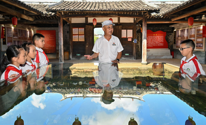  2026年7月24日，红军烈士后代、村里的红色讲解员钟鸣在中复村观寿公祠内为参加红色研学活动的小学生讲解。新华社记者 韩旭 摄