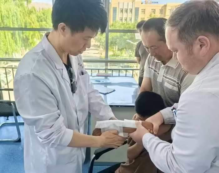 殷铭正在为柯尔克孜族骨折儿童进行手法复位后小夹板固定。无锡市中医医院供图