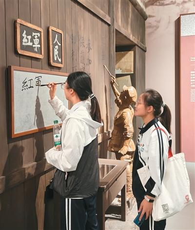参观展览的学生提笔写下“红军”。李在阳摄