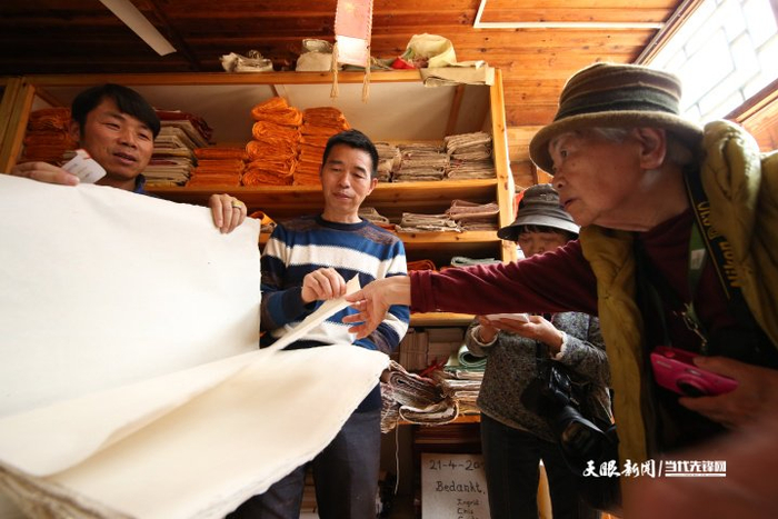贵州省丹寨县南皋乡石桥村手工皮纸展示馆，王兴武（左二）在向日本游客介绍新式白皮纸的质量。