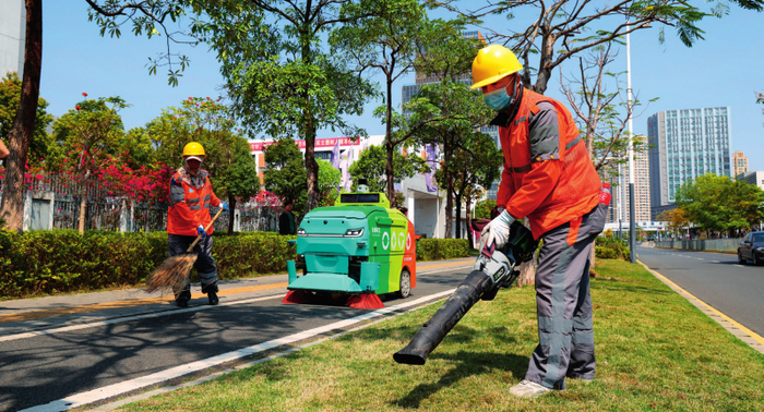 在深圳市坪山区石井街道，环卫机器人与环卫工人进行协同作业（2025 年 3 月 19 日摄） 毛思倩摄 / 本刊
