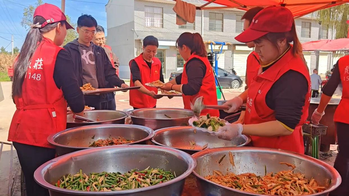 图为镇村干部和志愿者正在给老人打饭