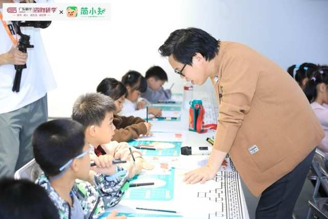 图：简小知与广东新华线下红色硬笔书法课堂上，王慧志老师现场指导学员规范书写