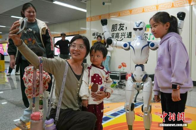  10月18日，河南郑州，市民与机器人在地铁东风路站拍照合影留念。中新网记者 范晓恒 摄