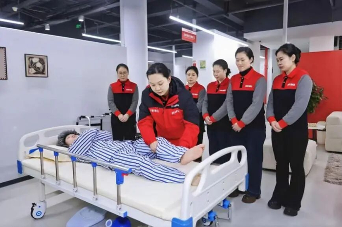 2025年12月30日，重庆市万州区，京东家政西南培训基地，培训师演示为失能老人进行肢体康复训练（受访单位供图）