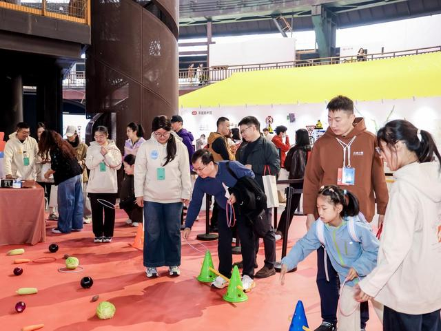 （图说：参观者在“大城小聚”互动展现场参加“民间小赛”的套圈比赛。）