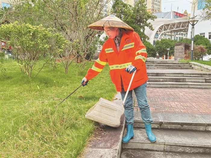 杨静清扫草地垃圾。本报记者 尹洁 摄