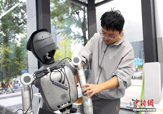 图为工程师在维修机器人。中新社记者 安源 摄
