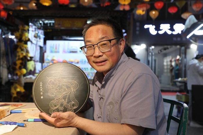   敦煌木雕画代表性传承人申洪杰在工作室展示木雕画作品《反弹琵琶》。新华社记者 张智敏 摄
