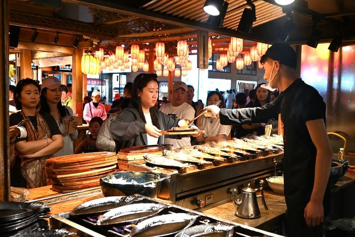   游客在敦煌夜市沙州食驿选购美食。新华社发（张晓亮 摄）