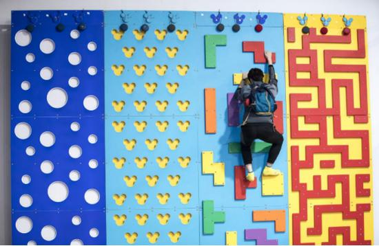 （主播攀岩为观众赢取福利，双肩包上的荣耀音乐小巨蛋十分便携）