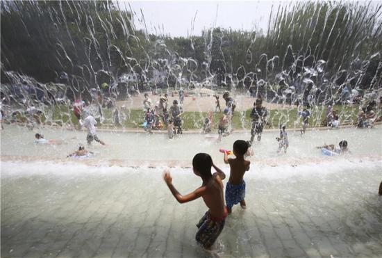 7月16日，在日本东京，孩子们在公园里的一处喷泉下玩耍。