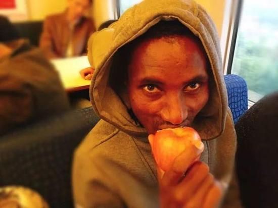 阿莫尼在动车上，吃中国乘客给他的苹果。