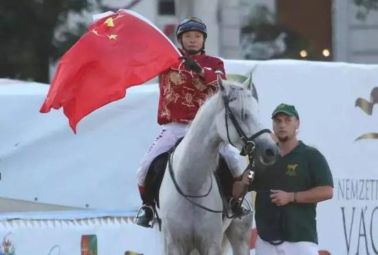 夺冠后的麻连凯骑着马，在布达佩斯的英雄广场上举着五星红旗绕场一周。