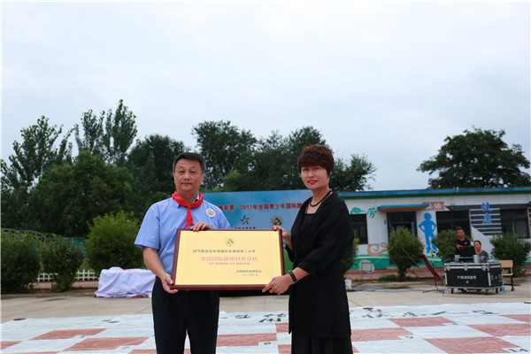 　　中国国际跳棋协会理事长葛峰（左）向秦皇岛市海港区东港镇第二小学校长马长缨（右）授予“全国国际跳棋特色学校”牌匾