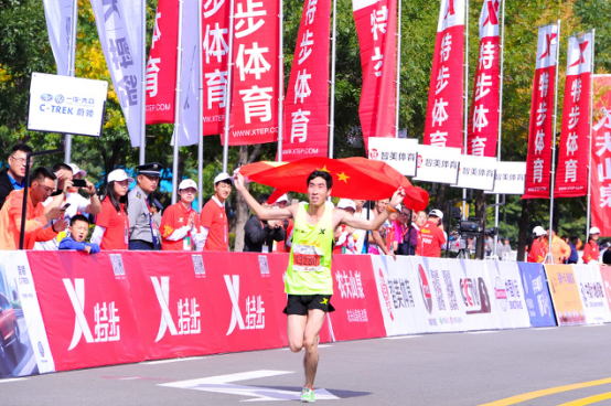 中国籍选手李健秋披着国旗冲线，获得男子全程第四名。