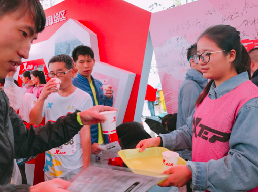 特步展区工作人员为真跑者分发热姜茶