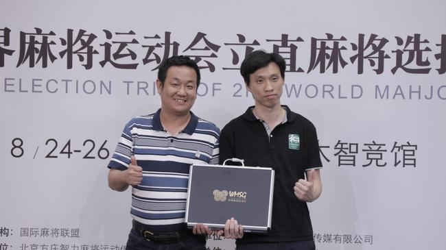 图：国际麻将联盟秘书长李文龙代表MIL向主办方明风智和赠送纪念品
