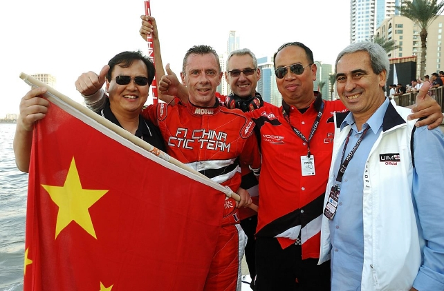 　　国际摩联F1委员会委员李浩杰（左一）手持国旗，祝贺中国天荣队蝉联2014-2016赛季“世界冠军”，成就“三连冠”伟业