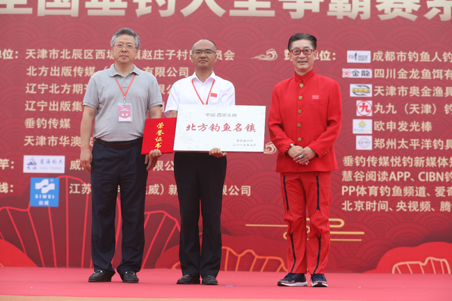 　　辽宁出版集团党委副书记赵庆国（左一）向西堤头镇授予“中国西堤头镇·北方垂钓名镇”名牌称号，六小龄童（右一）向西堤头镇授予相关荣誉证书，天津市北辰区西堤头镇镇长张富国接收牌匾及证书。