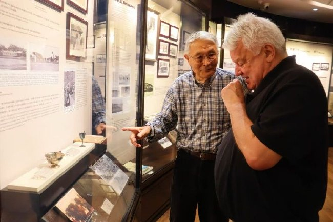 麦肯齐饶有兴趣地观看馆藏北京跑马场两只银质奖杯