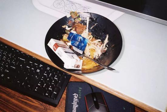 ▲网吧桌面随处可见的餐盘，而所有能够盛放物品的器皿都会被用来放烟屁股 | 来源：陈志贤《INTERNET CAFE! PANDA》&nbsp;