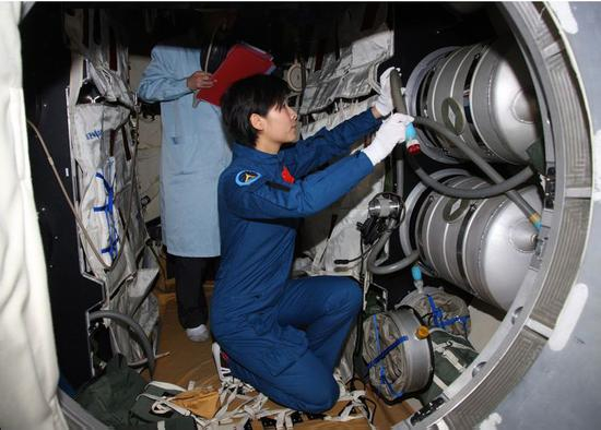 刘洋在天宫一号组合体模拟舱内检查实验设备（图片来源：http://www.91esh.com/）