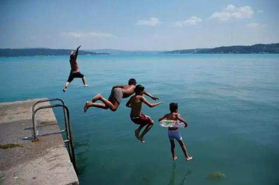 &nbsp;某个阳光灿烂的星期三，伊斯坦布尔的孩子们在满是浮游植物的博斯普鲁斯海峡边嬉戏。图片来源：Lefteris Pitarakis /美联社